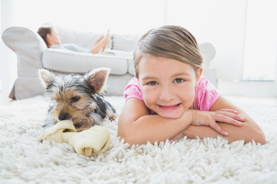 Yong child and pet dog laying on a carpet